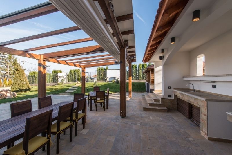 Metal louvered pergolas and timber eaves. There is a bbq area and outdoor furniture